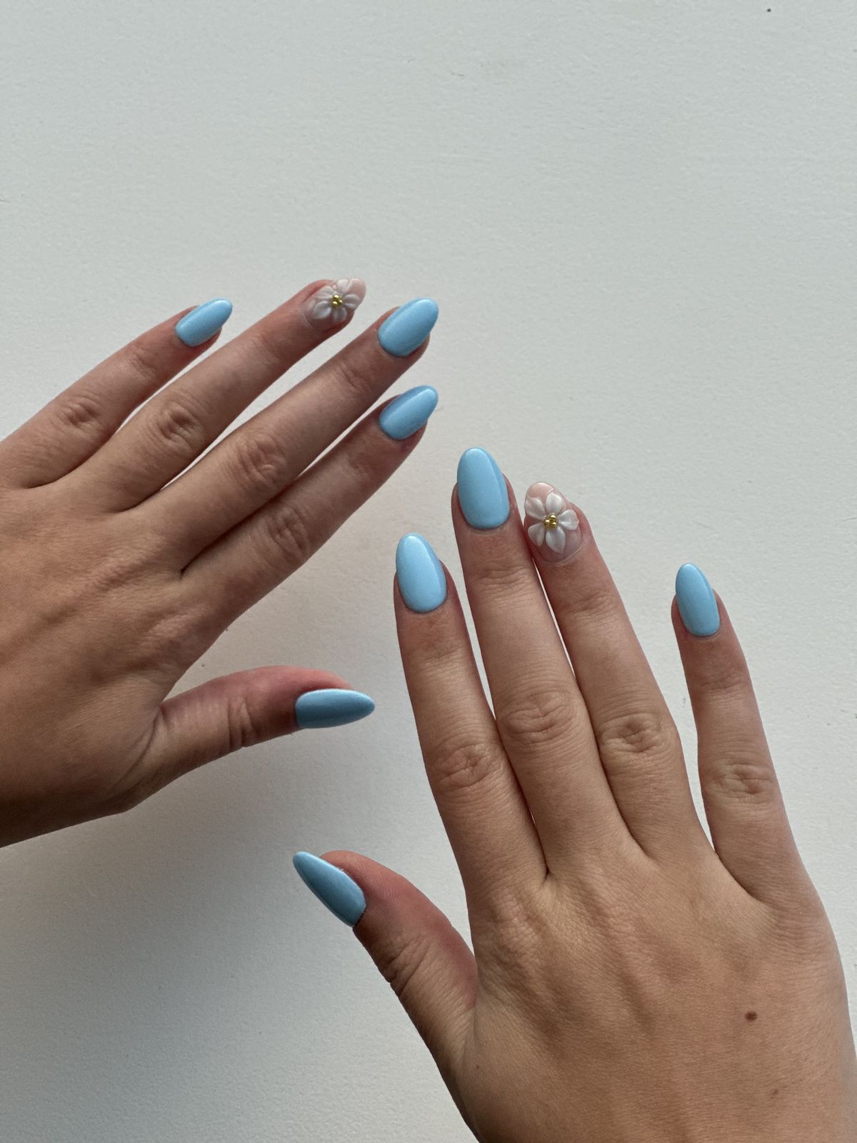 Hemelsblauwe amandelnagels met een klein bloemetje, foto van een klant